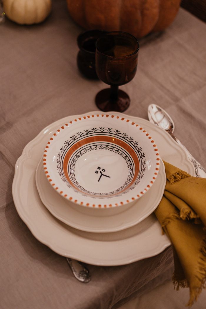 our-services-02 Close-up of a stylish ceramic bowl and plate setting with silverware on a rustic table.