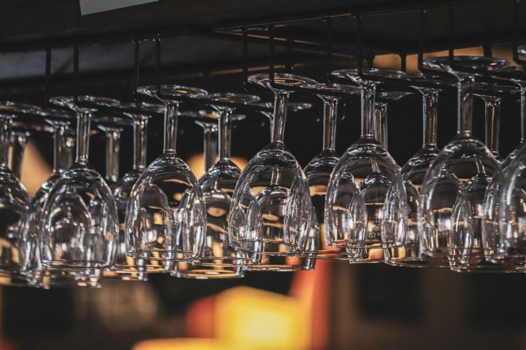 Close-up shot of upside-down wine glasses hung on a rack in a softly lit bar.